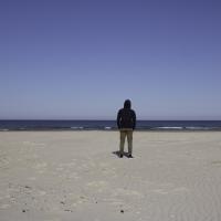 Ung mand står alene på strand