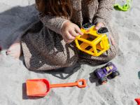 Lille pige i sandkasse leger med en lille gravemaskine