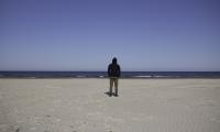 Ung mand står alene på strand